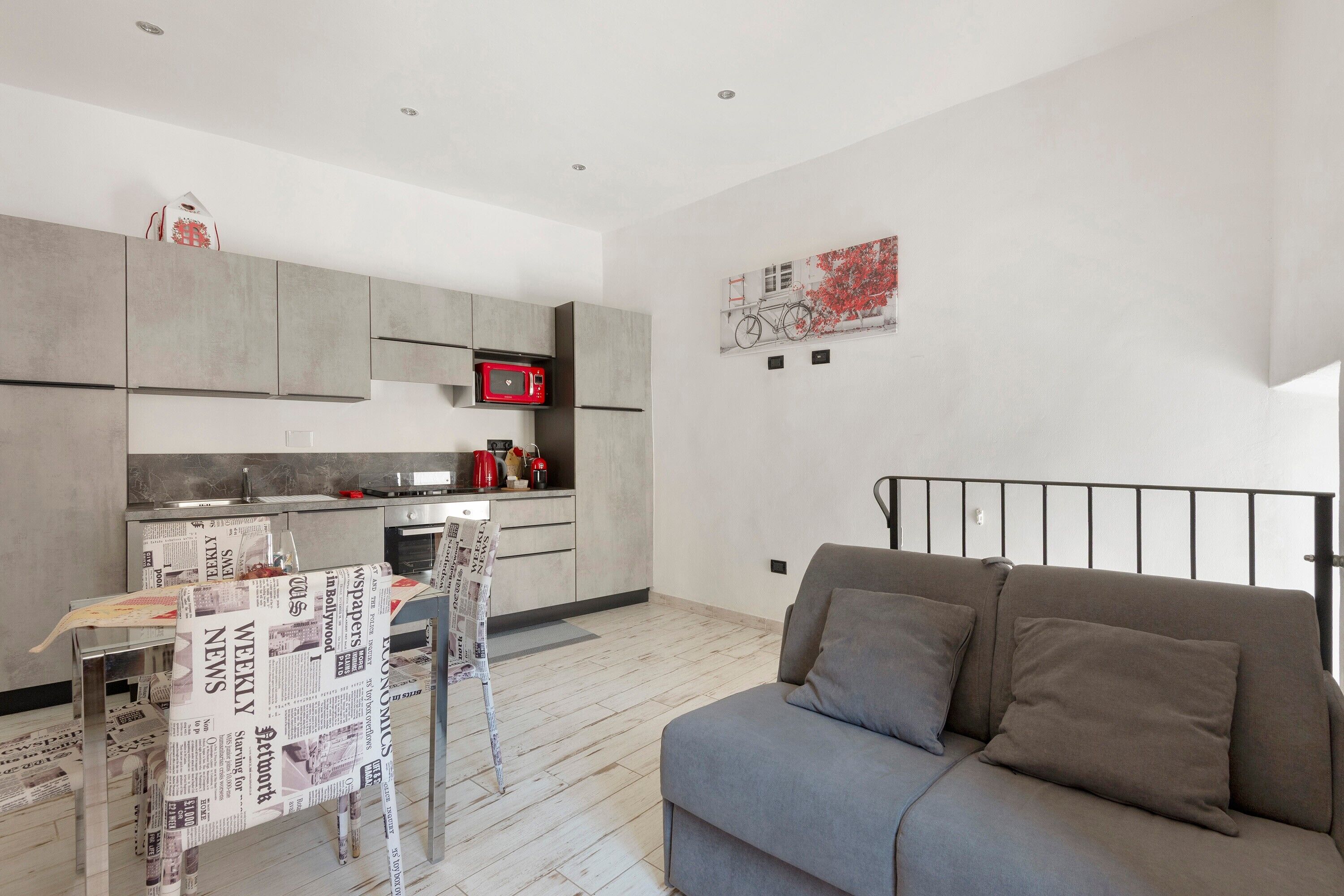 A modern kitchen with grey cabinets, a microwave, and a dining table covered with newspapers.. Apartment 'Casa Gaby' with Air Conditioning