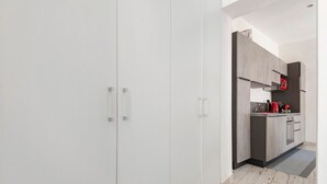 A modern kitchen with grey cabinets, a black refrigerator, and a red kettle.