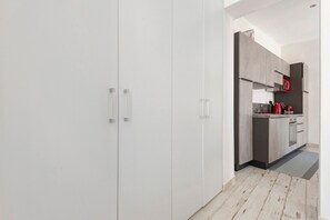 A modern kitchen with grey cabinets, a black refrigerator, and a red kettle.