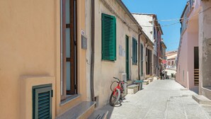 A narrow street with buildings, a red bicycle, and a person walking.