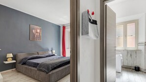 A modern bedroom with a bed, bedside table, and a painting on the wall.