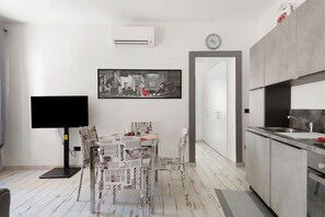 Ett modernt kök med en inbyggd ugn, en matplats med bord och stolar samt en tv med platt skärm.