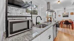 A kitchen with a built-in microwave, stainless steel sink, and a dining area with a table and chairs. - Horizon Hideaway Hot Tub Fire Pit Game Room (Long Pond)