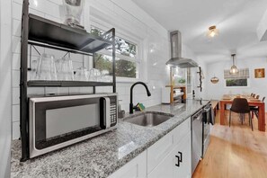 A kitchen with a built-in microwave, stainless steel sink, and a dining area with a table and chairs. - Horizon Hideaway Hot Tub Fire Pit Game Room (Long Pond)