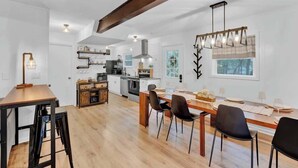 A spacious kitchen with modern appliances, a dining area with wooden tables and chairs, and a large window providing natural light. - Horizon Hideaway Hot Tub Fire Pit Game Room (Long Pond)