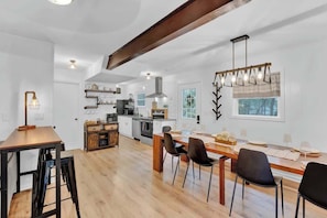 A spacious kitchen with modern appliances, a dining area with wooden tables and chairs, and a large window providing natural light. - Horizon Hideaway Hot Tub Fire Pit Game Room (Long Pond)