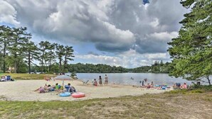 A lakeside beach with people relaxing, a grassy area, and trees. - Horizon Hideaway Hot Tub Fire Pit Game Room (Long Pond)