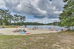 A lakeside beach with people relaxing, a grassy area, and trees. - Horizon Hideaway Hot Tub Fire Pit Game Room (Long Pond)