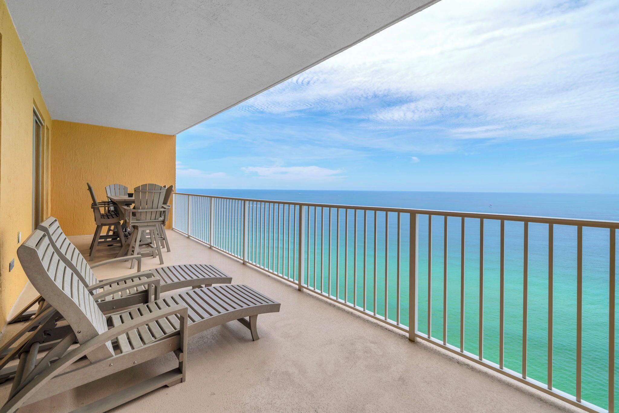 Ein Balkon mit Lounge-Möbeln und Tisch, mit Blick auf ein klares Meer.