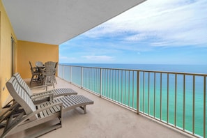 Ein Balkon mit Lounge-Möbeln und Tisch, mit Blick auf ein klares Meer.