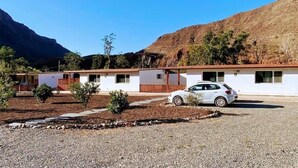 Une rangée de bâtiments blancs d’un motel, avec une voiture garée devant.