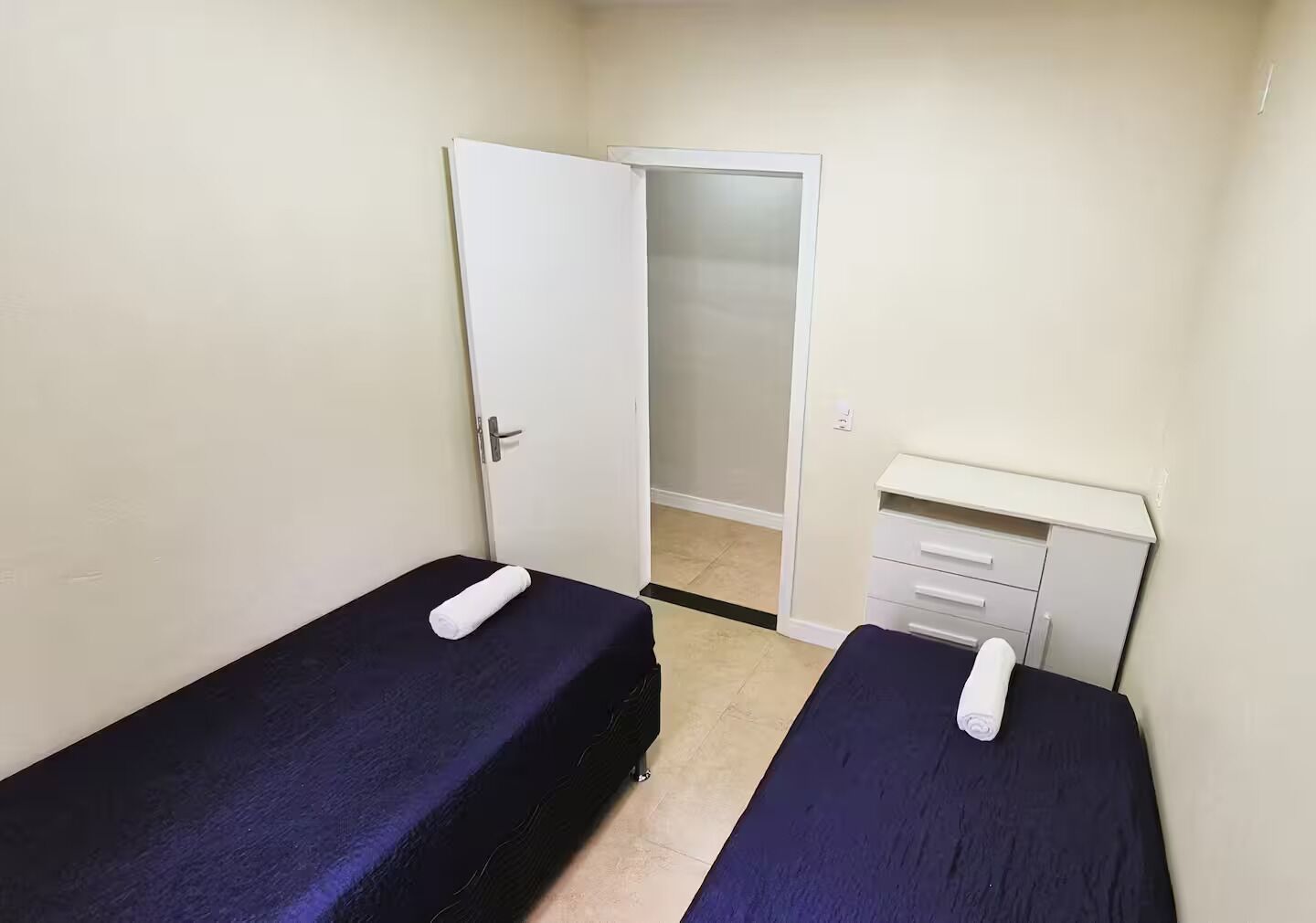 Une petite chambre avec deux lits simples, une armoire et un bureau.