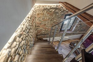 Eine Holztreppe mit Steinwänden und Metallgeländern.