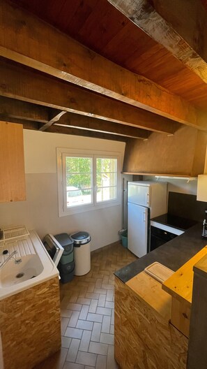 Eine kleine Küche mit Fenster, Spüle und Kühlschrank.