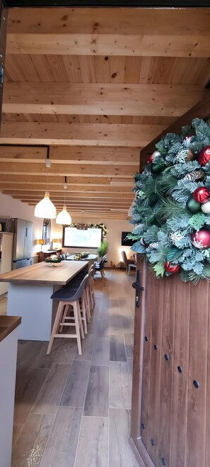 A modern kitchen with wooden beams, a central island with bar stools, and a festive Christmas tree.