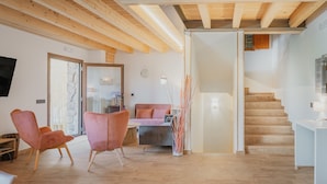 A modern living room with wooden beams, a staircase, and a dining area.