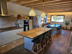 A modern kitchen with a central island, bar stools, and pendant lighting.