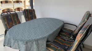 Ein Essbereich mit einem runden Tisch, vier Stühlen und Blick auf ein Gebäude mit Balkonen.