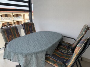 Ein Essbereich mit einem runden Tisch, vier Stühlen und Blick auf ein Gebäude mit Balkonen.