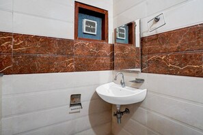 Un baño con un lavamanos blanco, un espejo y un sistema de ventilación.