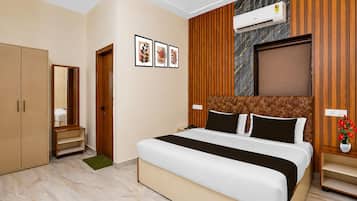 A hotel room with a bed, wardrobe, vanity, and a wall-mounted air conditioner.