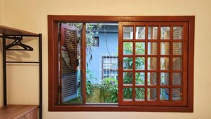 Una ventana con vista a un edificio azul y follaje.