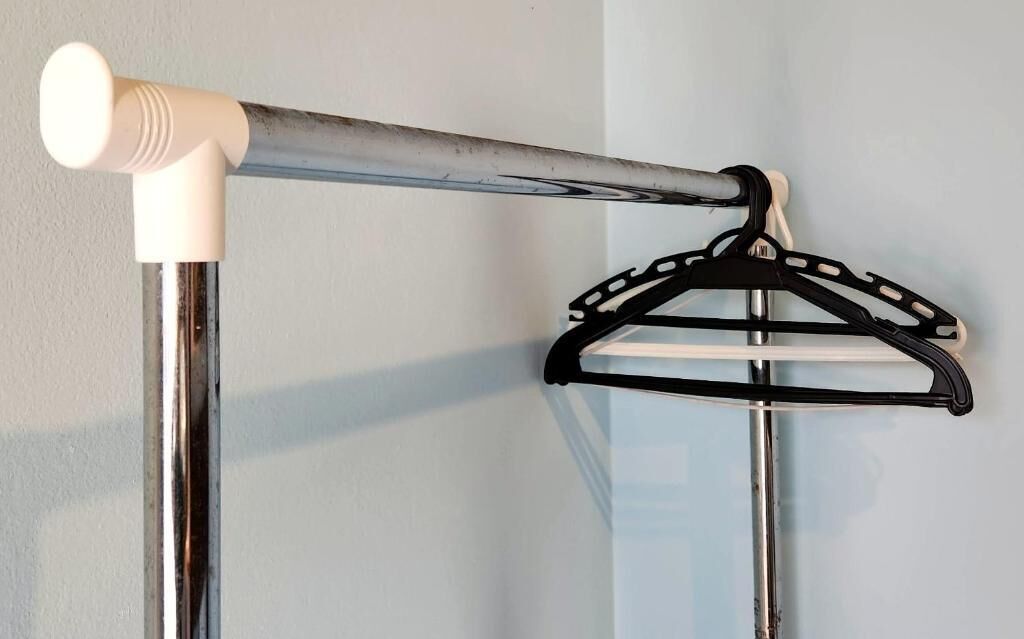 Metallinen teline, jossa on valkoinen sylinterimäinen esine ja musta henkari.