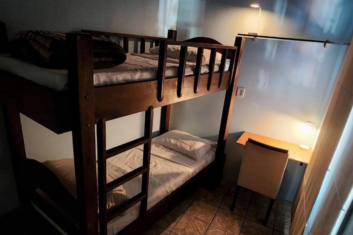 A bunk bed room with a desk and a lamp.