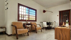 Una habitación con dos sillas color beige, una mesa de madera, una ventana con vistas y una puerta.