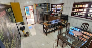 A kitchen with a gas stove, refrigerator, and dining table with chairs. - Casa Maré - Coliving and Coworking (Florianópolis)