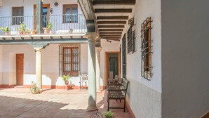 Un patio con una banca, plantas en macetas y un balcón.