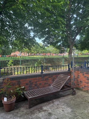 A bench, a brick wall, a metal fence, and a tree in a park setting. - Boho Retro 4-bedroom house in charming Headingley for your Leeds stay (Leeds)