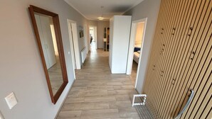 A hallway with wooden flooring, white walls, and a large mirror on the left. - Vacation home Inseltraum Bauernhof-Claussen (Fehmarn)