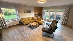 A living room with a sofa, armchair, coffee table, and a view of the outdoors. - Vacation home Inseltraum Bauernhof-Claussen (Fehmarn)