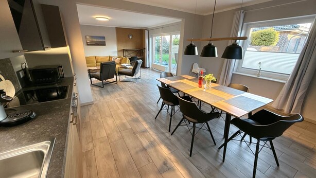 A modern kitchen with a dining area, wooden flooring, and pendant lights. - Vacation home Inseltraum Bauernhof-Claussen (Fehmarn)