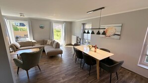Een moderne woonkamer met een bank, eettafel, stoelen en uitzicht op de omgeving.