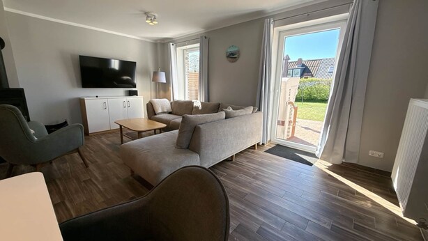 Een moderne woonkamer met een bank, een televisie, een lamp en uitzicht op buiten.