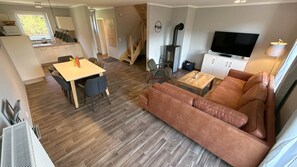 Ein modernes Wohnzimmer mit einer Couch, einem Fernseher und einem Essbereich.