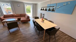 Ett modernt vardagsrum med en soffa, ett matbord med stolar, en klocka och ett fönster med gardiner.