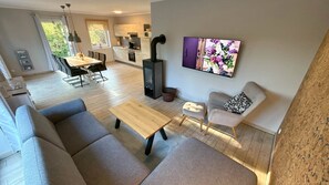 Ein modernes Wohnzimmer mit einer Couch, einem Couchtisch, einem Kamin, einem Essbereich und einer Küche im Hintergrund.