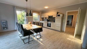 Eine moderne Küche mit Essbereich, Holzboden und Pendelleuchten.