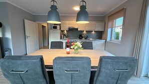A modern kitchen with two pendant lights, a dining table with four chairs, and a vase with flowers. - Vacation home Seestern Bauernhof-Claussen (Fehmarn)