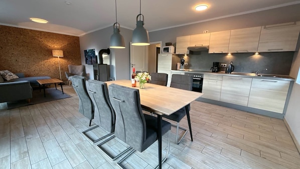 A modern kitchen with a dining area, a sofa, and a fireplace. - Vacation home Seestern Bauernhof-Claussen (Fehmarn)