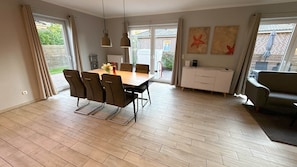 A dining area with a table and chairs, a radiator, a cabinet, and artwork on the wall. - Vacation home Seestern Bauernhof-Claussen (Fehmarn)