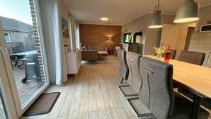 A modern kitchen with a dining area, a sofa, and a TV. - Vacation cottage Sonne Bauernhof-Claussen (Fehmarn)