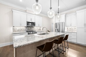 A modern kitchen with white cabinets, a granite countertop, stainless steel appliances, and pendant lighting. - Blue Mountain 30A! Golf Cart and Bikes! Pool Access (Santa Rosa Beach)