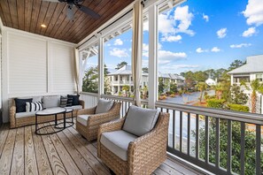 A covered porch with wicker furniture, a ceiling fan, and a view of neighboring houses.