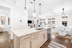 A modern kitchen with granite countertops, a built-in sink, and pendant lighting.