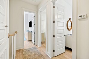 Ein Flur mit weißen Türen, einem Webteppich und einem Thermostat an der Wand.