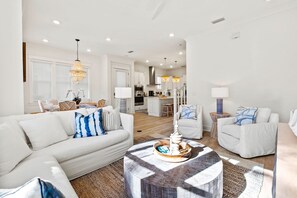 Ein modernes Wohnzimmer mit einem weißen Sofa, einem runden Couchtisch und einem Essbereich im Hintergrund.